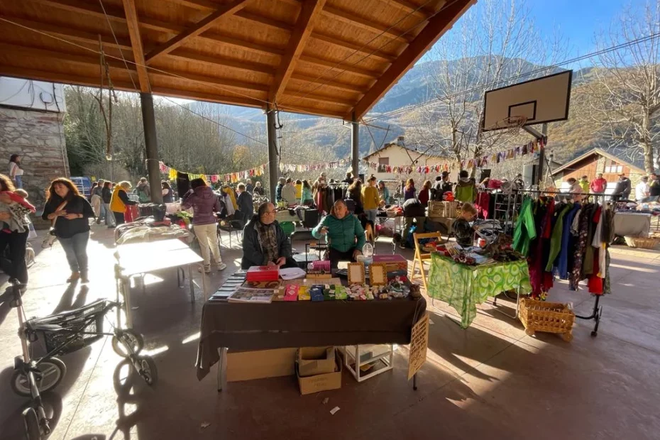 Puesto del Centro 'el Remós' entre los distintos puestos del Mercau Circular celebrado en Sesué. Se ve a personas visitando los puestos, que están colocados bajo una estructura techada en Sesué.