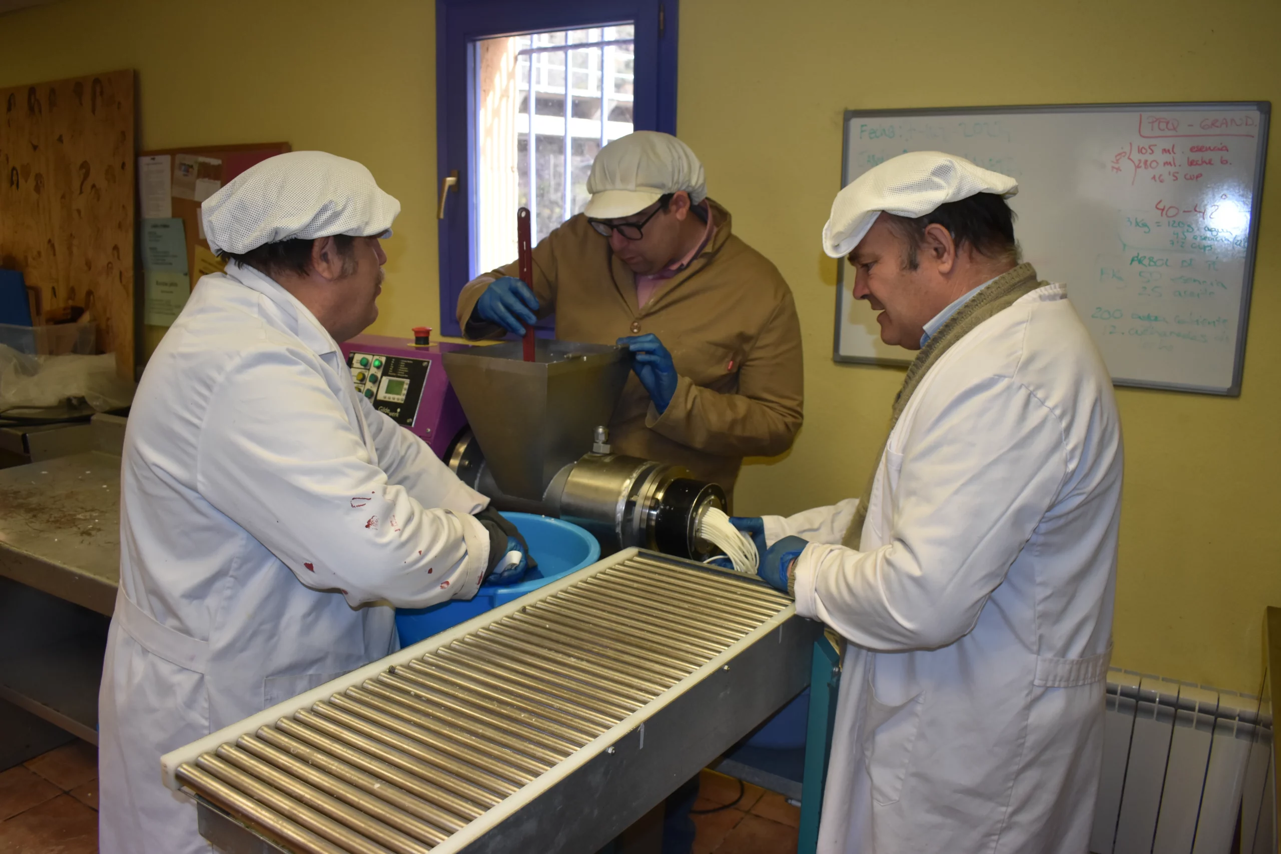 Tres operarios fabrican jabón alrededor de la máquina en el taller de El Remós.